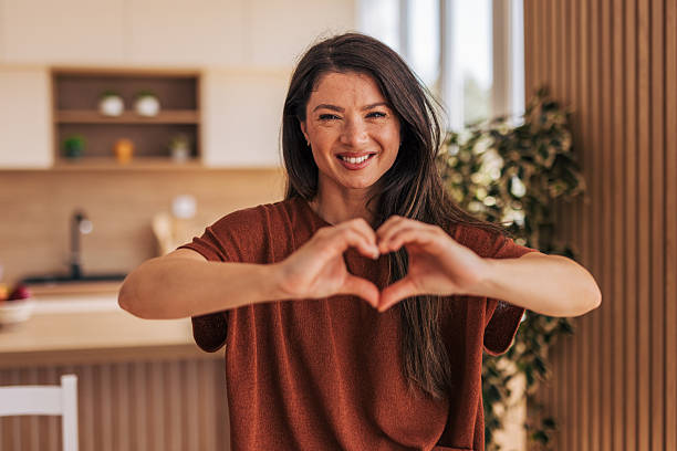 istock Brunette woman making heart shape with hands in kitchen 2220526910