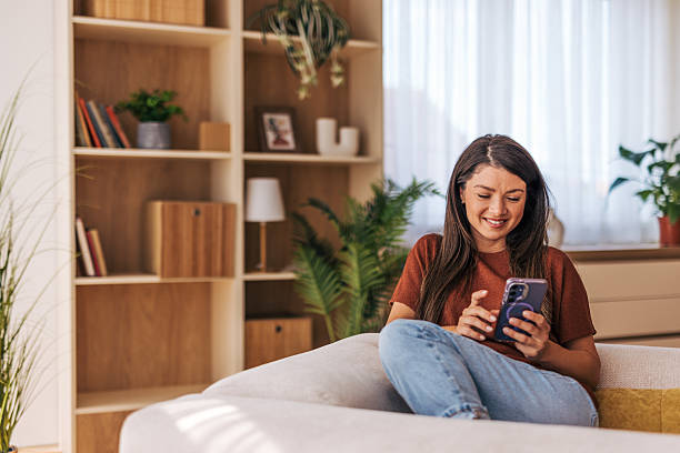 istock Young woman relaxing on sofa using smartphone at home 2220527036