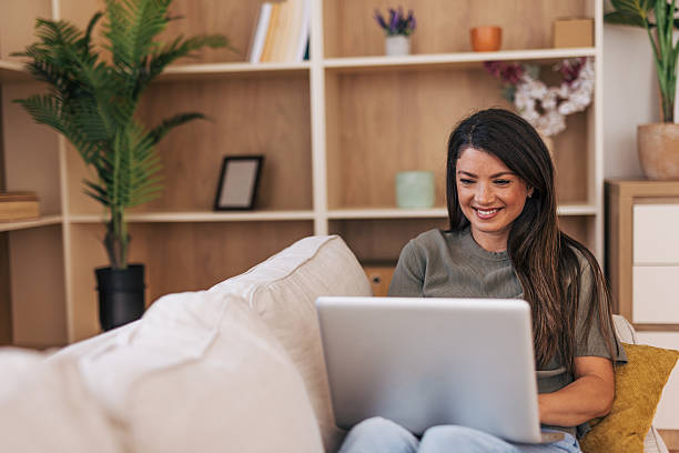 istock Young woman working remotely from home office using laptop on sofa 2220528662