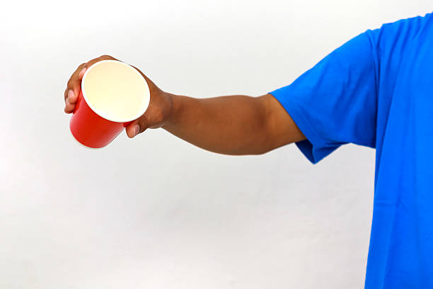 Hand holding a red paper cup, isolated on a white background in studio shot