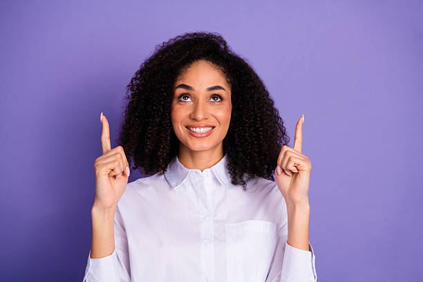 istock Confident young woman gestures upwards with both hands against a violet background emphasizing optimism and opportunity 2220534276