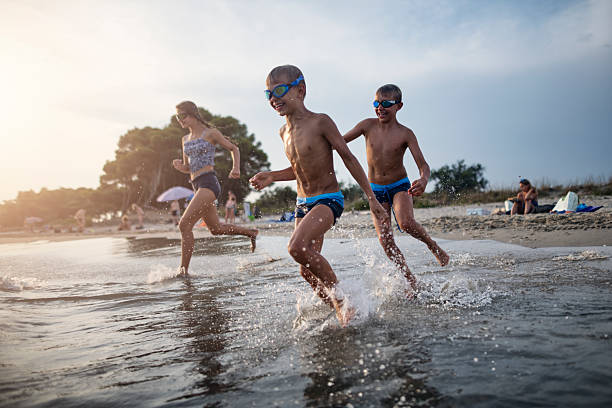 istock Children running into shallow sea on a sandy Tuscan beach. 2220535594