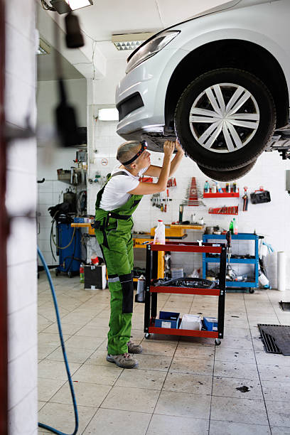 istock Car Lifted in Garage as Female Mechanic Fixes Components 2220536040