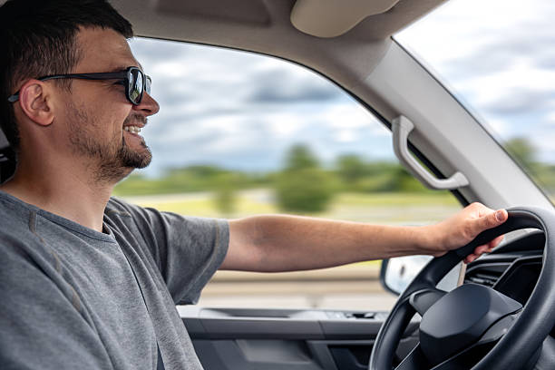 istock Smiling man driving car. Relaxed road trip. Driver in motion. 2220539064