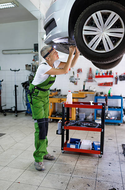 istock Female Mechanic Using Wrench Underneath Elevated Car 2220540292