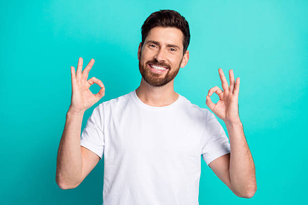 istock Happy man in casual attire making okay gesture with both hands against turquoise background 2220540318