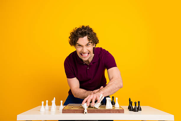 istock Young man playing chess with a confident expression against a bright yellow background enhancing modern style 2220540516