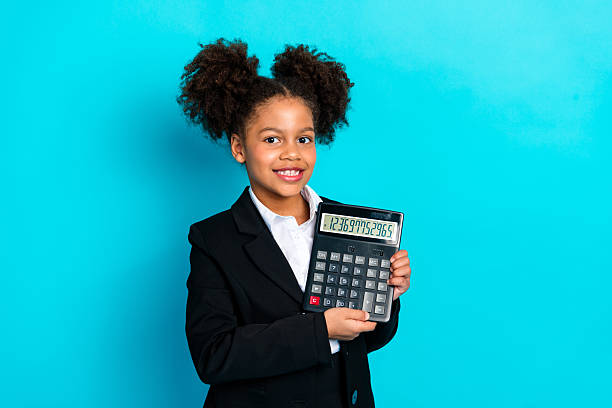 istock Confident young student holding a large calculator in a formal suit against a bright turquoise background with a charming smile 2220541326