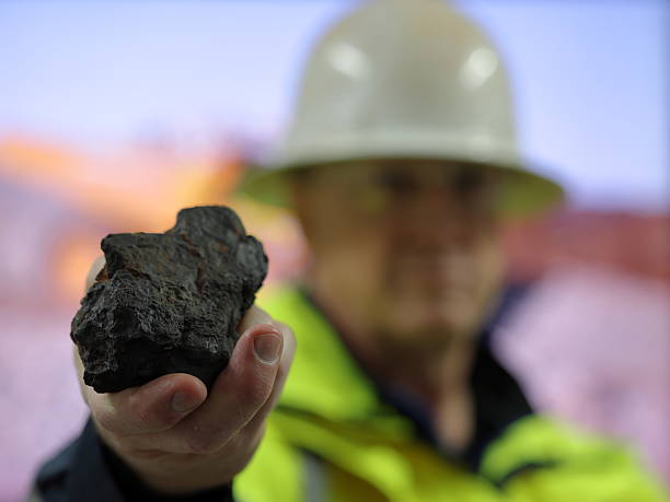 istock Manganese ore held by geologist, metallurgist, towards camera. Blurred background, differential focus. Mn mine, mining, critical mineral used in stainless steel and batteries 2220545744