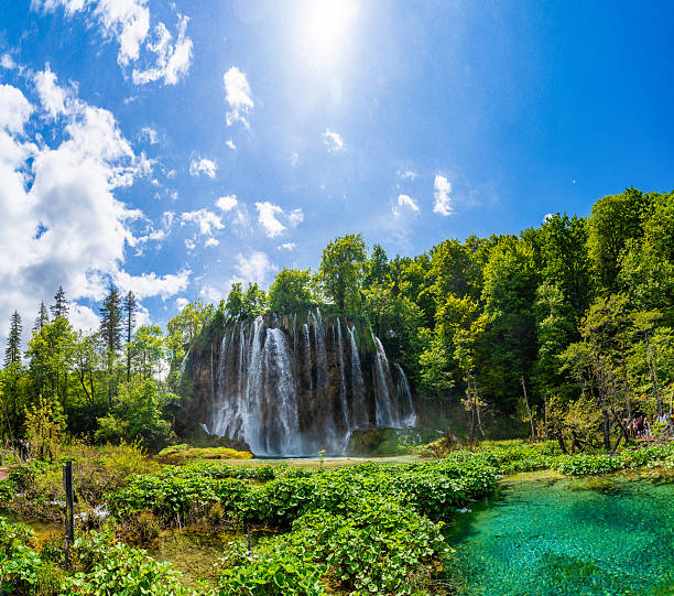 istock Wide Panoramic View of Large Waterfall Surrounded by Dense Greenery and Reflective Water in Plitvice Lakes National Park, Croatia 2220551597