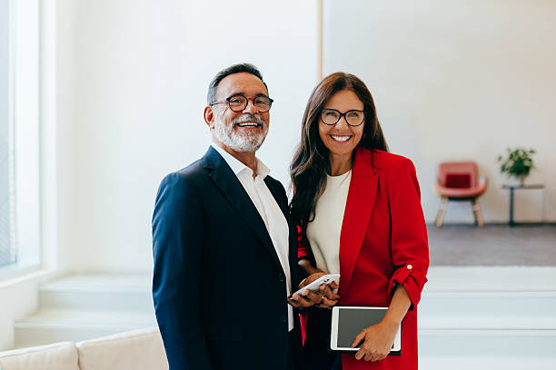 istock Smiling senior management with electronic devices in a bright, open office space 2220551783