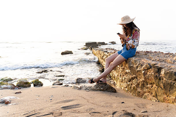 istock Tourist relaxing on a spanish beach using smartphone at sunset 2220551863