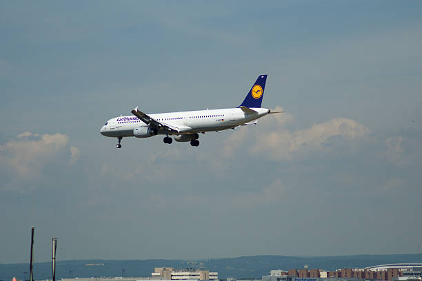 A Lufthansa Airbus A320 is captured during its final approach to Frankfurt Airport. The aircraft, with its distinctive blue and yellow tail livery, is framed against a clear sky, just moments before touching down. This image highlights the precision and coordination involved in landing procedures at one of Europes major aviation hubs.