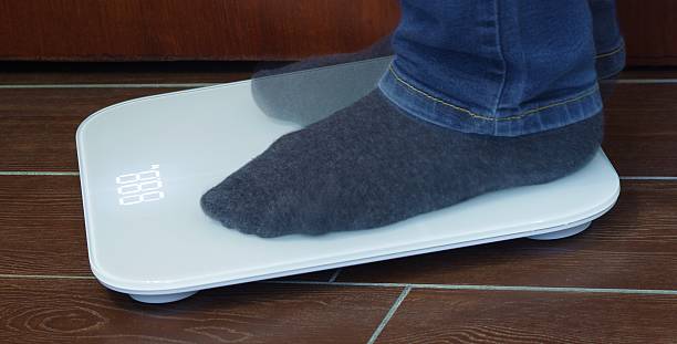 istock Man weighs himself on the scales 2220556425
