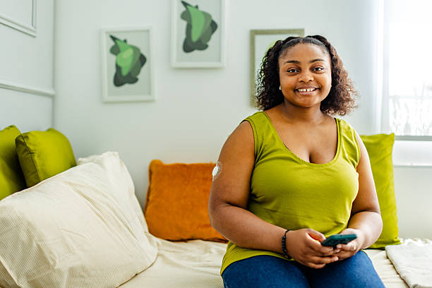 istock Young black woman managing type 1 diabetes on a cozy sofa in her stylish bedroom while using a smartphone 2220556533