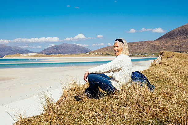 Woman walking along the dunes at Luskentyre beach on the west coast of Harris in the Outer Hebrides of Scotland. To be picky, it’s the beach beside Luskentyre, called Seilebost.