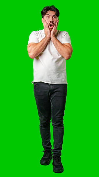istock Young man expresses surprise in front of a bright green background 2220560446