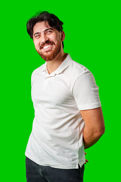 istock A smiling young man with a beard poses against a bright green background 2220562464