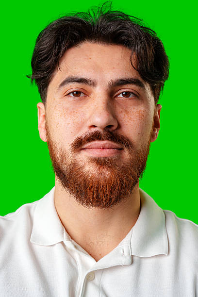 istock A smiling young man with a beard poses against a bright green background 2220565758