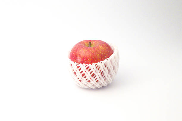 A red apple wrapped with a cushioning net with white background