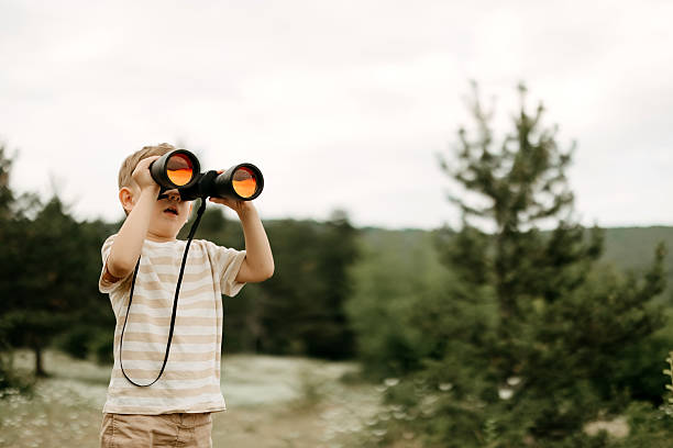 istock Young boy looking through binoculars, outdoors 2220569068