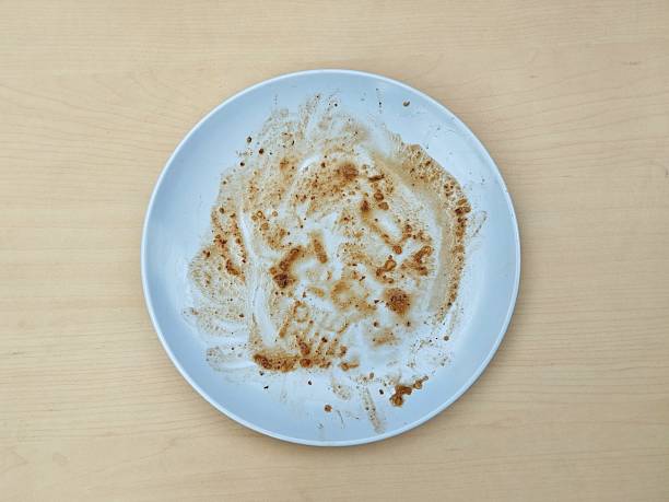 istock Dirty white plate with leftovers food on wooden table background 2220569956