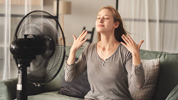 istock Woman cooling down by ventilator at home 2220570090