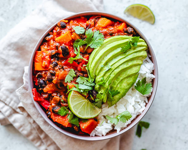 Overhead view of a bowl of vegan homemade chili sin carne served with rice and avocado
