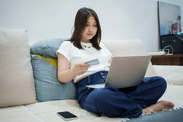 istock Asian woman sitting on sofa checking bank statement 2220571686