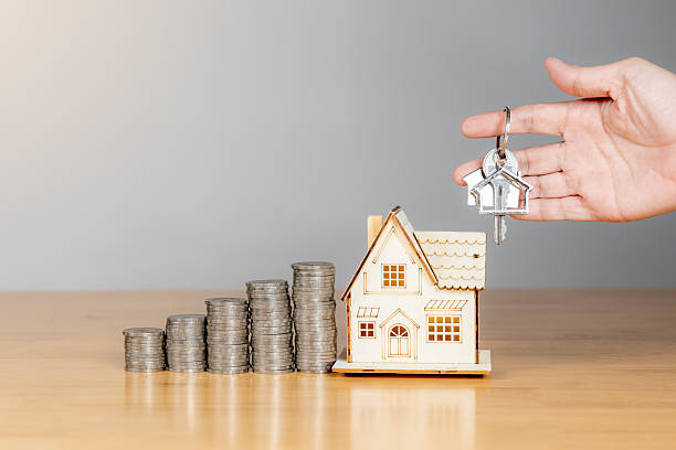 istock Hand holding house key with small home model on table  new home ownership concept 2220573000