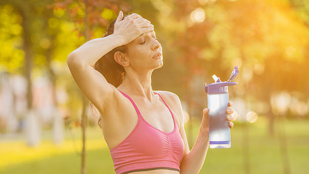 Woman drinking water in park. Heat wave