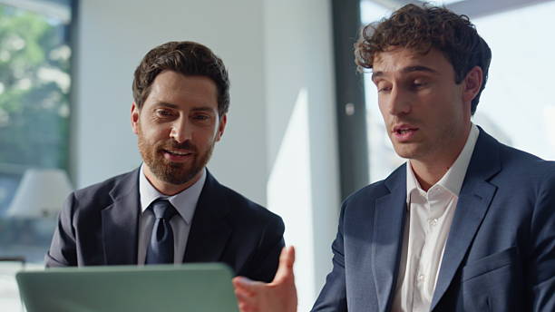 istock Smiling business colleagues videocalling laptop modern cafeteria table closeup 2220574619