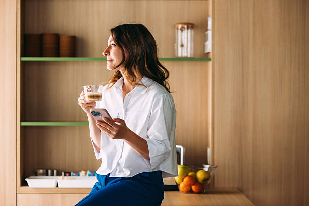 Woman Relaxing with Coffee and Smartphone in a Modern Kitchen Setting