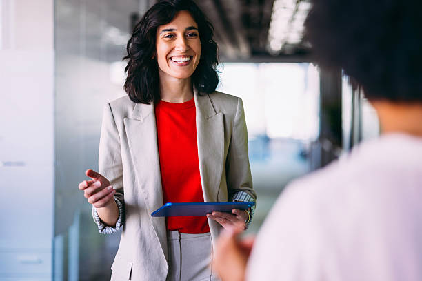 Smiling Businesswoman Holding a Tablet During an Office Discussion
