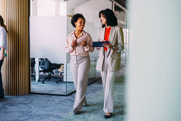 istock Two Businesswomen Discussing Ideas While Walking in a Modern Office Setting 2220578594