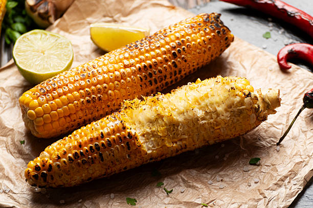 istock Half eaten grilled corn on cob with lime and other spices on wooden table 2220580058