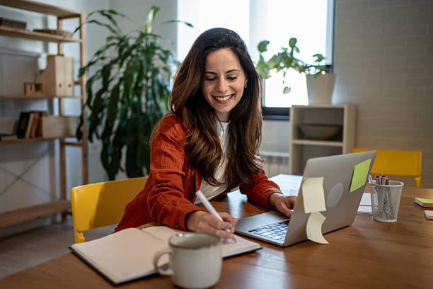 istock Young businesswoman working from home taking notes and using laptop 2220584533