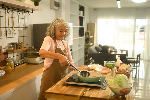 istock A smiling elderly Asian woman prepares breakfast in a kitchen, Morning Cooking Routine 2220585128