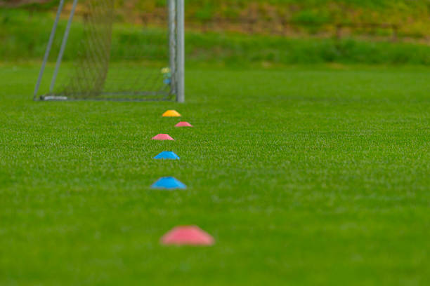 Teenage girl training herself for soccer in city backyard. She is from middle eastern descent and is wearing red traditional soccer clothing. Horizontal close-up on feet outdoor shot with copy space. No face. This was taken in Montreal, Quebec, Canada.