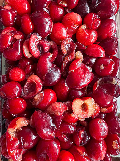 Stock photo showcases fresh red cherries that have been deseeded but still retain their stems, capturing vibrant summer fruit ready for jam making. The rich color and juicy texture highlight the cherries’ freshness, emphasizing home-style preservation and seasonal produce