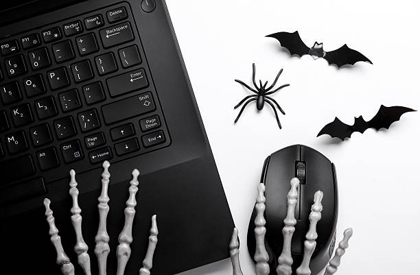 istock Skeleton hands using laptop with halloween decor on white background. Top view 2220593796