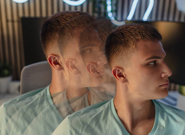 Artistic portrayal of a young man with multiple exposure effects, creating a surreal visual impact. The subject wears casual attire and gazes aside, set within a modern indoor environment.