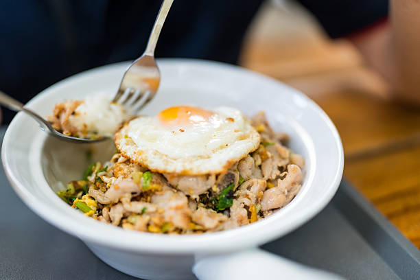 Man eating steamed pork on rice and fried egg. Close up