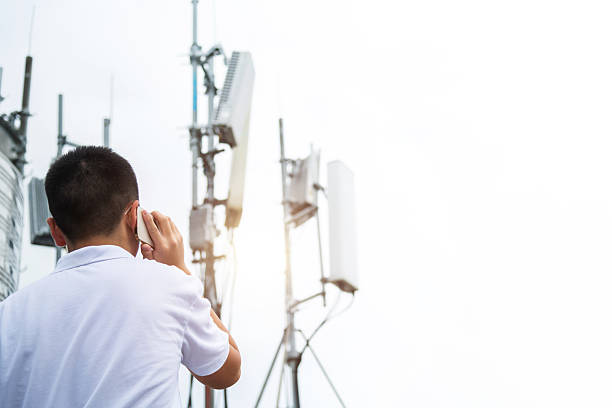 istock Teenage boy using mobile phone near 5G communications tower 2220598643