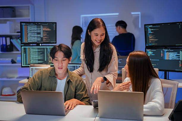 istock young Asian software development manager leads a late-night office discussion with his executive team, mentoring developers and analyzing source code to guide programming and project development 2220599129