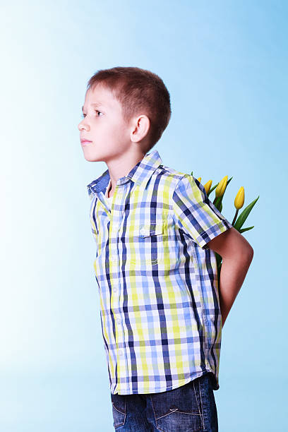 Special occasions holiday and mother day. Young boy prepare surprise gift flowers hold tulips behind back.