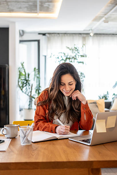 istock Young woman working from home taking notes in her notebook smiling 2220599804