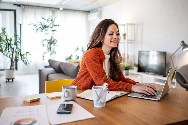 Young businesswoman working from home using laptop computer at the wooden table