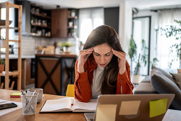 istock Stressed young woman having headache while working from home 2220600105