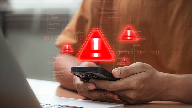 istock Cybersecurity threat warning on smartphone with red alert icon signaling hacking attempt, virus infiltration, and data breach while user checks phone at home, showing mobile cyberattack risk 2220600281